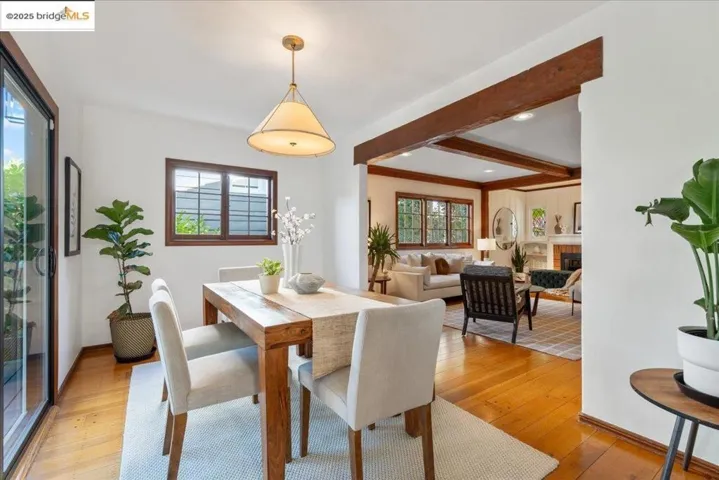 Dining space with beam ceiling, light wood-style floors, and a fireplace