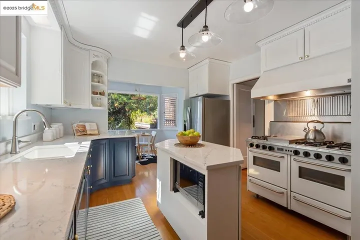 Kitchen featuring stainless steel appliances, white cabinets, open shelves, under cabinet range hood, and light stone countertops