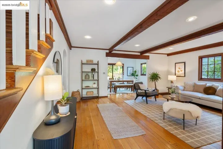 Living room featuring hardwood / wood-style flooring, beamed ceiling, stairway, recessed lighting, and crown molding
