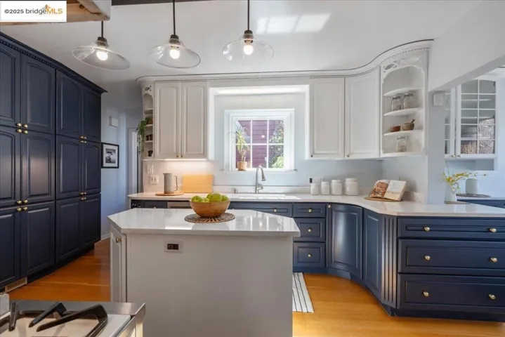 Kitchen with open shelves, white cabinetry, light wood-style flooring, and light stone countertops