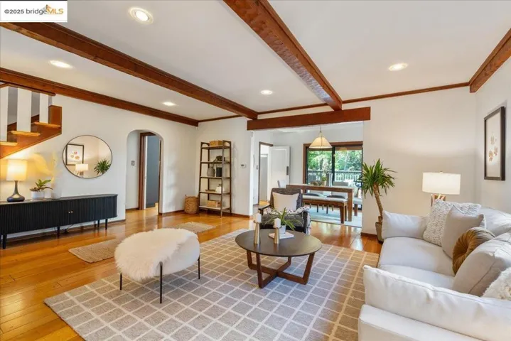Living area featuring hardwood / wood-style flooring, beamed ceiling, arched walkways, recessed lighting, and stairs