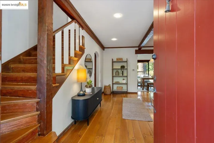 Hall featuring wood-type flooring, arched walkways, ornamental molding, recessed lighting, and stairs