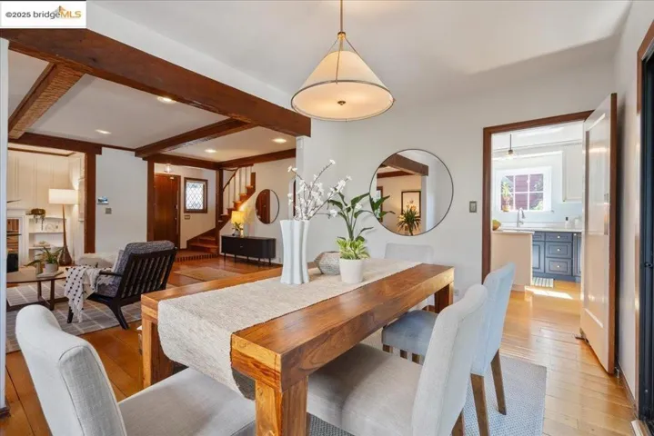 Dining space with light wood-type flooring, beam ceiling, stairway, and recessed lighting