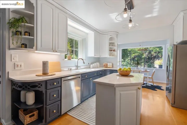 Kitchen featuring open shelves, white cabinets, appliances with stainless steel finishes, light wood-type flooring, and light stone countertops