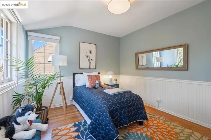 Bedroom featuring wainscoting, wood finished floors, and vaulted ceiling