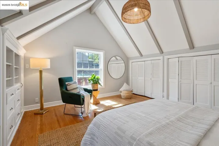 Bedroom featuring beam ceiling, wood finished floors, two closets, and high vaulted ceiling