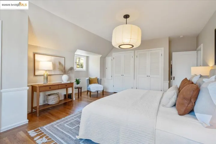 Bedroom with wood finished floors, two closets, and vaulted ceiling