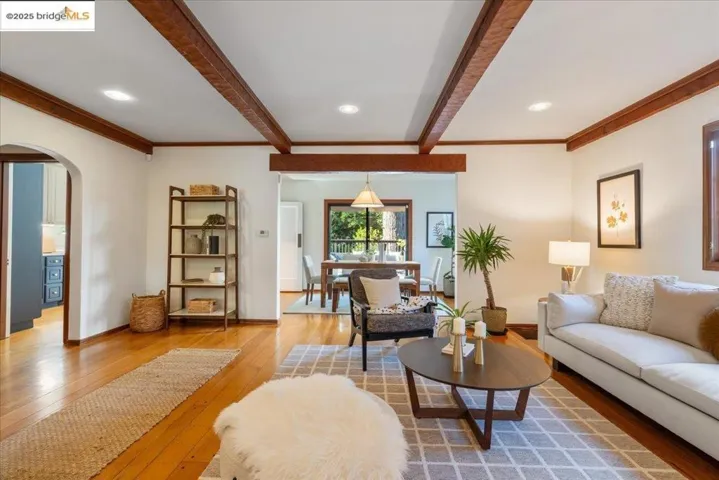 Living room featuring arched walkways, light wood-type flooring, beam ceiling, recessed lighting, and ornamental molding
