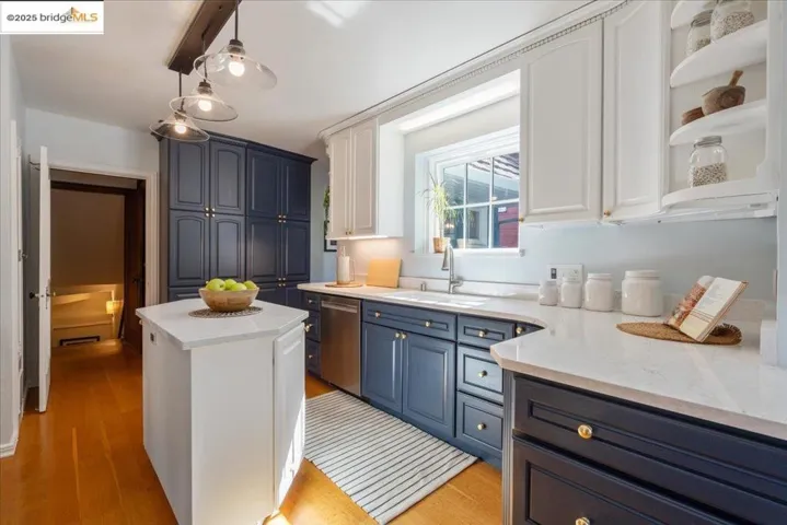 Kitchen featuring blue cabinets, light stone countertops, white cabinetry, light wood-style floors, and stainless steel dishwasher