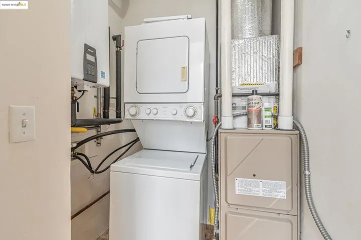 Laundry room with estacked washer and dryer, tankless water heater, and heating unit