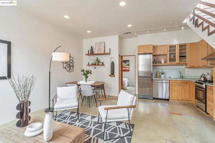 Open floor Kitchen/Dining room with appliances with stainless steel finishes, wooden cabinets, open shelves, recessed lighting, and light stone counters