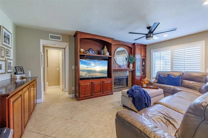 View into the family room with fireplace and custom built-in cabinetry, from the formal entry and living room. The doorway on the left leads to the downstairs bedroom and guest bath