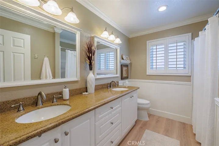Upstairs completely remodeled hall bath features a double-sink vanity, custom cabinetry, custom tile work in the tub/shower, and lots of light