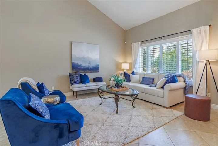 Living room features large format floor tile, cathedral ceilings, plantation shutters, and designer paint