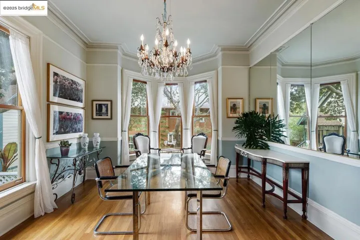 Dining area with wood finished floors, a chandelier, and ornamental molding