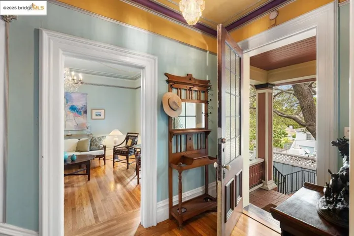 Entryway with a chandelier, ornamental molding, and wood finished floors