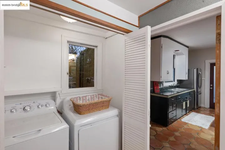 Washroom with washing machine and dryer and tile patterned flooring