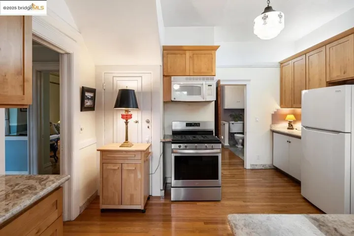 Kitchen featuring white appliances, light wood-type flooring, and hanging light fixtures