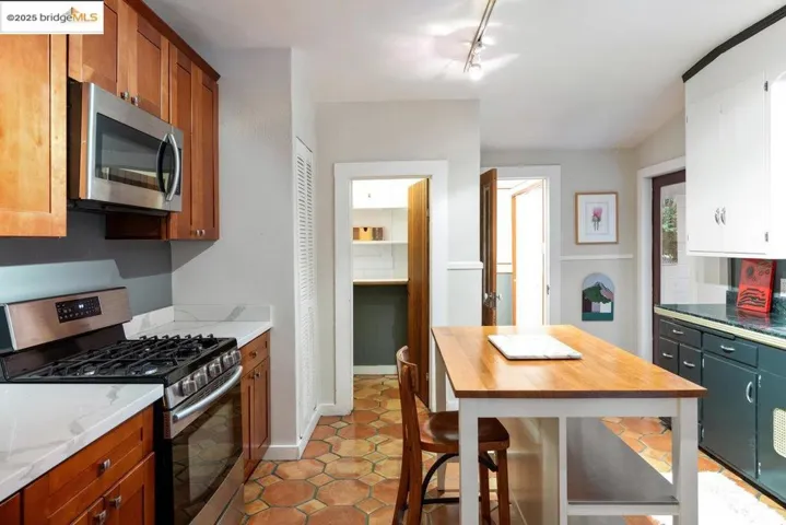 Kitchen featuring stainless steel appliances, light tile patterned flooring, light stone counters, and brown cabinets