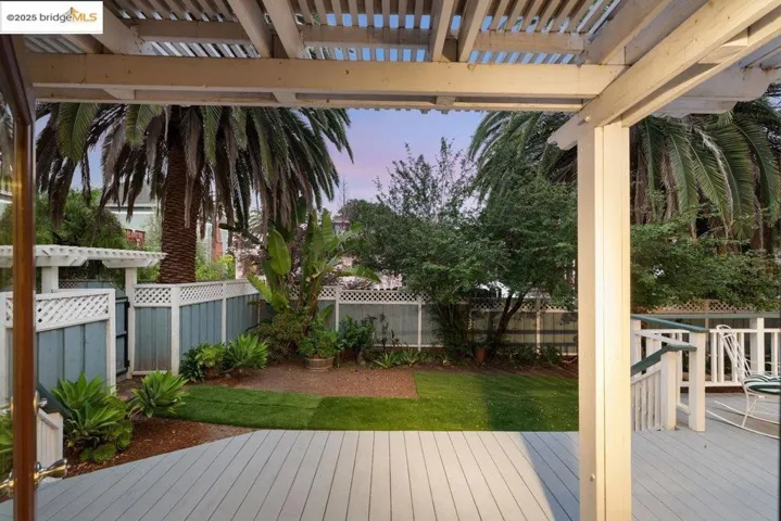 Deck at dusk featuring a fenced backyard and a pergola