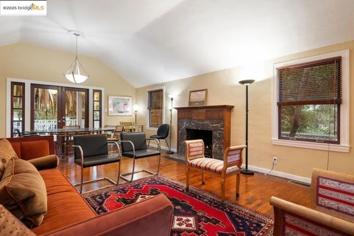 Living area featuring french doors, wood finished floors, a fireplace, plenty of natural light, and lofted ceiling