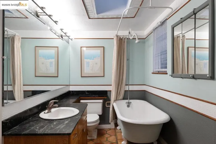 Full bath with vanity, tile patterned flooring, and a combined bath / shower with freestanding tub