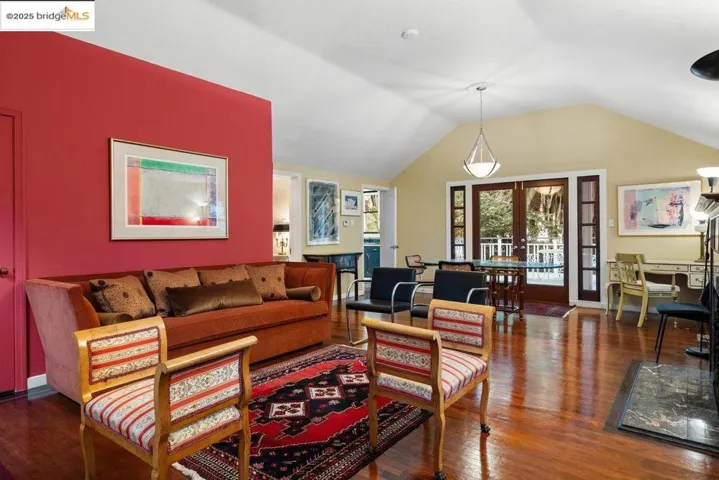 Living room featuring french doors, dark wood-style floors, and lofted ceiling