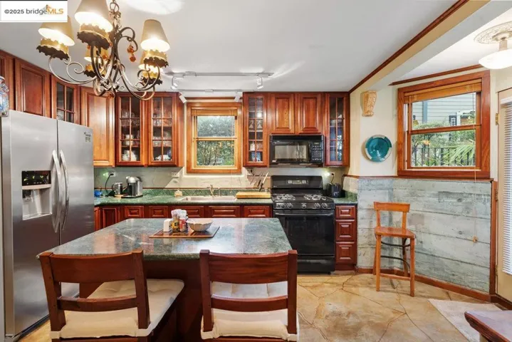 Kitchen with pendant lighting, black appliances, a chandelier, and a kitchen bar
