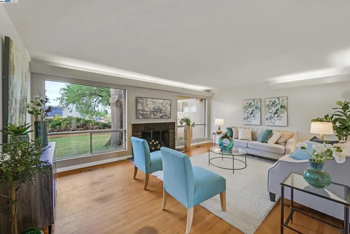 Living room has picture windows, a cozy fireplace and original hardwood floors.