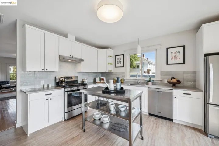 Kitchen with appliances with stainless steel finishes, hanging light fixtures, white cabinets, light countertops, and light wood-style floors