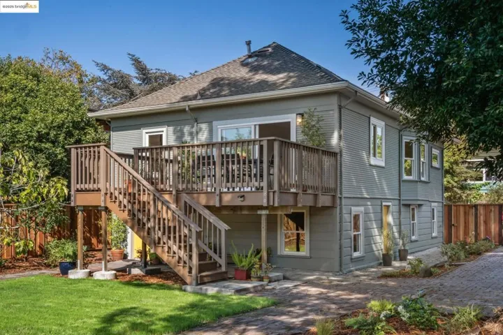 Back of house featuring stairway, a deck, and roof with shingles