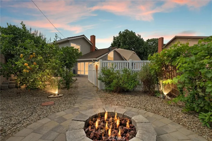Stunning backyard oasis with exterior illumination and newer fire pit and pavers to surround the butterfly and fruit tree garden.
