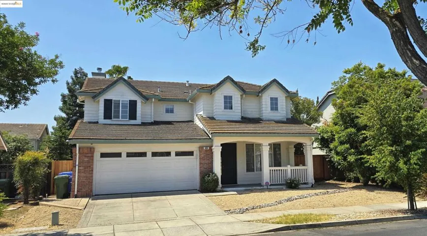 Traditional-style house featuring a tiled roof, a porch, brick siding, concrete driveway, and a garage