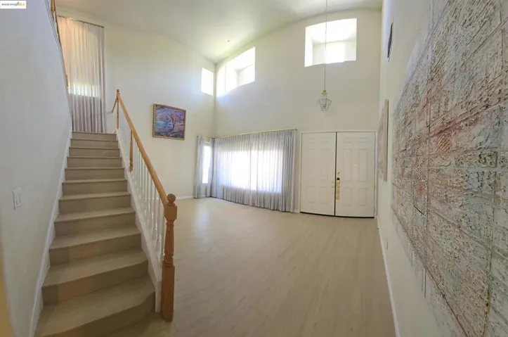 Entrance foyer with stairs, wood finished floors, and a high ceiling