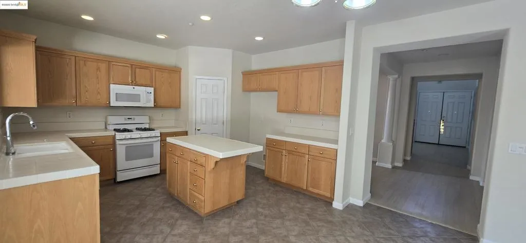 Kitchen with a center island, white appliances, recessed lighting, and tile counters