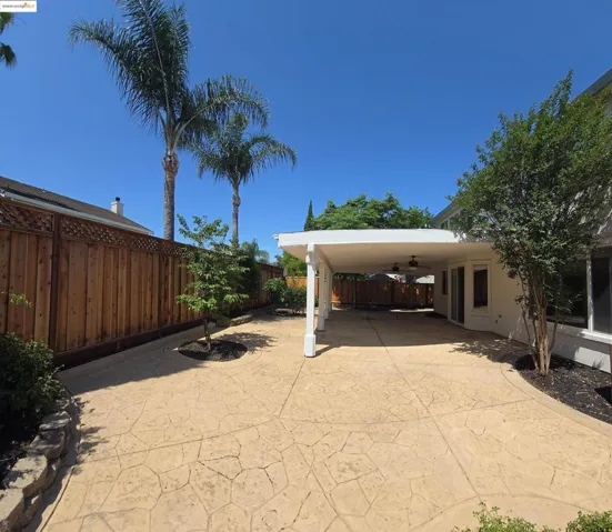 Fenced backyard with a ceiling fan and a patio area