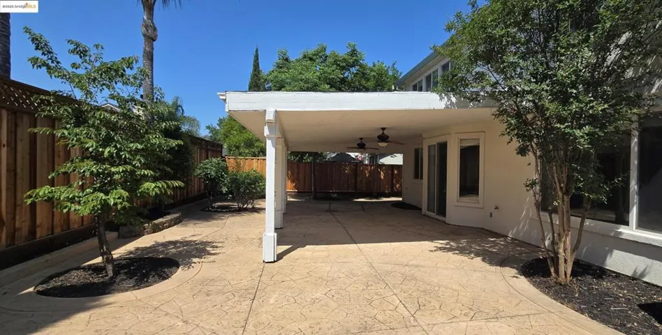 Fenced backyard with a patio area and ceiling fan