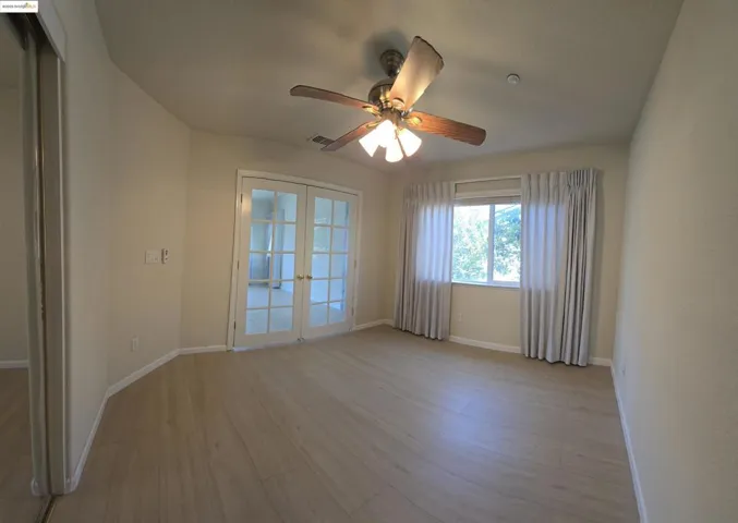 Spare room featuring french doors, light wood-style floors, and ceiling fan