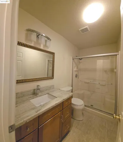 Full bath featuring a stall shower, vanity, a textured ceiling, and light tile patterned floors