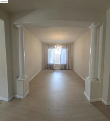 Unfurnished dining area with decorative columns, a chandelier, and light wood-style flooring
