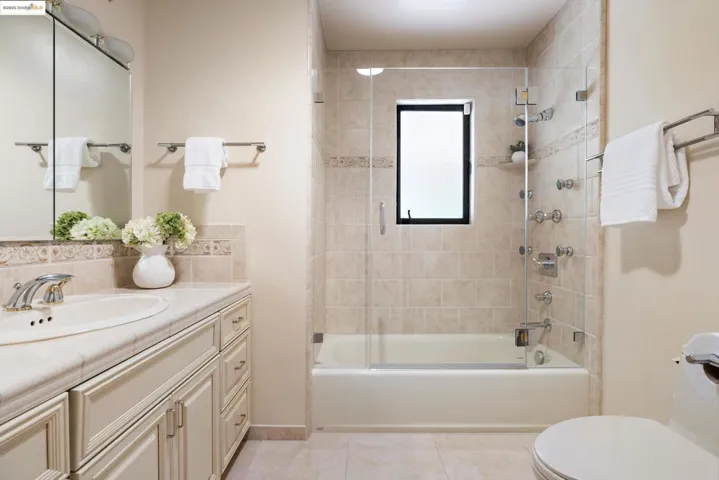Bathroom with bathing tub / shower combination, vanity, light tile patterned floors, and decorative backsplash