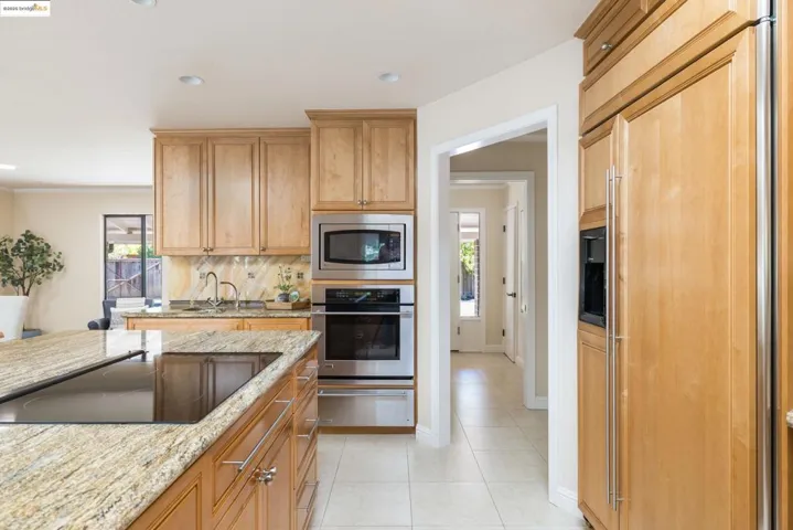Kitchen with built in appliances, a warming drawer, light stone countertops, backsplash, and recessed lighting