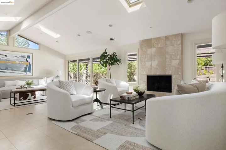 Living room featuring a skylight, a fireplace, light tile patterned flooring, and recessed lighting