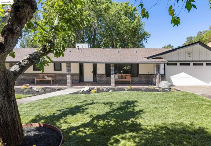 Ranch-style home featuring a shingled roof, a front lawn, and brick siding