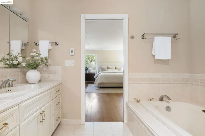 Ensuite bathroom featuring vanity, a bath, and light tile patterned floors