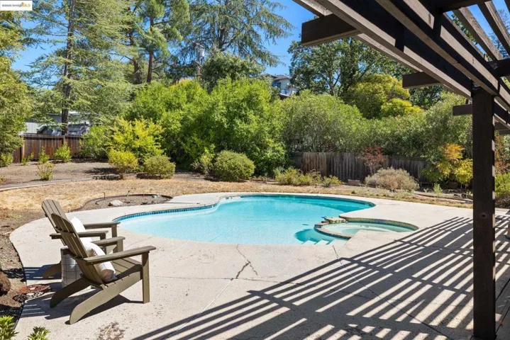 View of swimming pool featuring a pool with connected hot tub, a fenced backyard, and a patio