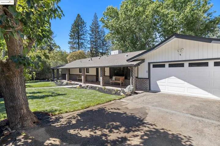 Single story home with brick siding, a front lawn, driveway, a shingled roof, and a garage