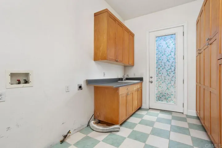 Laundry room with lots of cabinets, sink & folding area.  Door to back patio all brick.