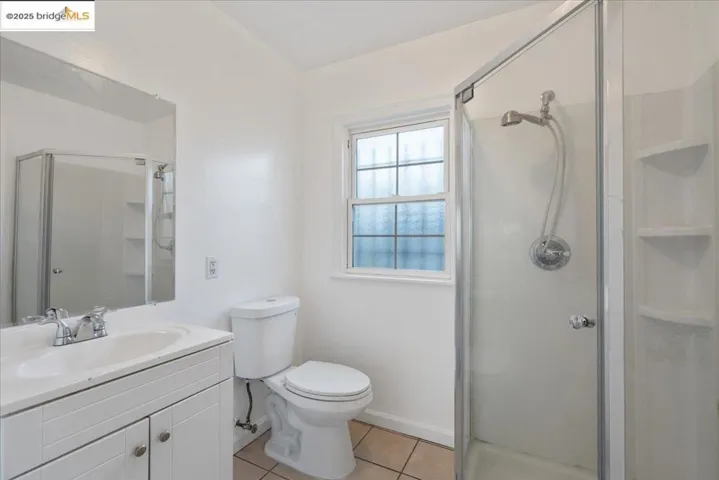 Full bath featuring a shower stall, vanity, and light tile patterned floors