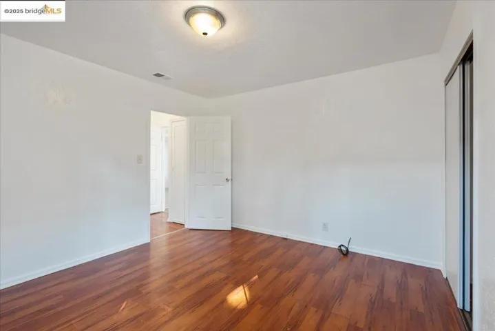 Empty room featuring dark wood finished floors and baseboards